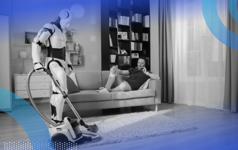 A robot vacuums while a man makes a phone call on the couch