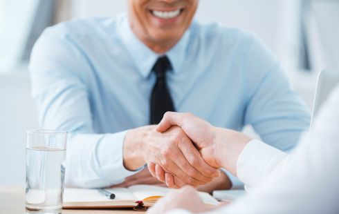 A job applicant shakes hands with a hiring manager at a job interview.