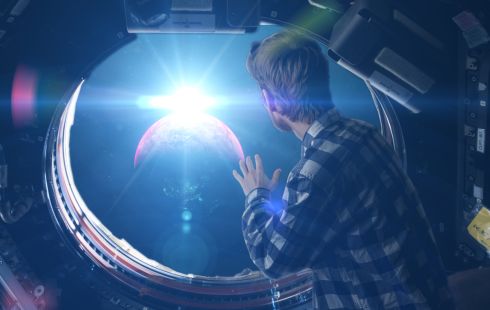 Image of a man looking out of the window of a spaceship, as if he's looking out the window of a plane.