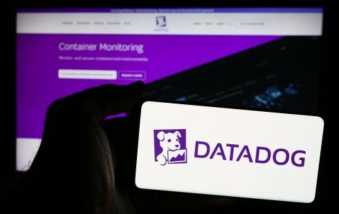 The Datadog logo on an iPhone with a computer screen in the background showing the Datadog website