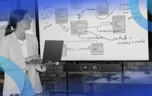 A woman presents with a laptop in front of a whiteboard
