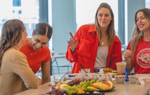 A photo of CarGuru employees talking around a kitchen table in an office setting.