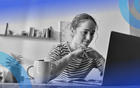 A remote worker looks at her laptop with a cup of coffee nearby