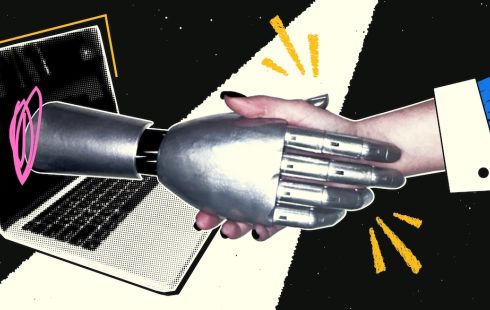 An employee shakes a robotic hand coming out of a laptop screen.