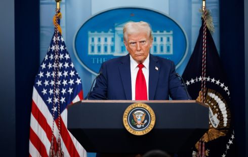 Image of Trump standing behind a podium, with an American flag in the background.