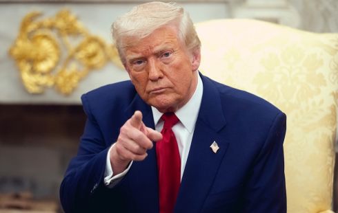 Image of President Trump pointing in front of him, wearing a blue suit and red tie with a white collar shirt.