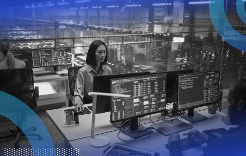 IT workers on terminals in an office with glass walls