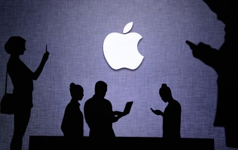 Silhouettes of people using technology in front of Apple logo