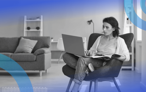 A woman sits in a chair with a laptop in a living room