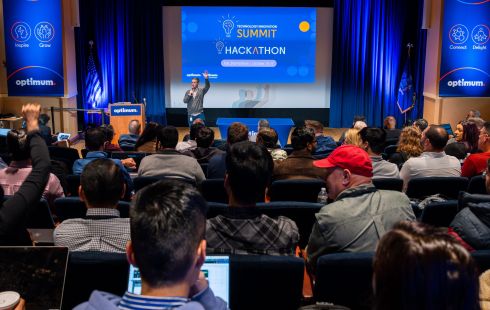 A group of Optimum employees in the audience of a hackathon.