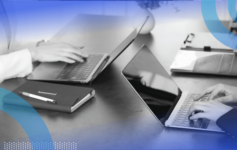 A closeup on developers working on laptops with a notebook on the table