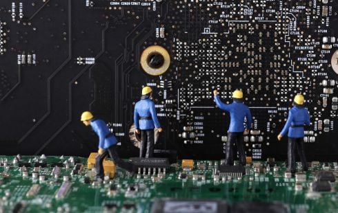 An image of miniature figures working on a computer’s motherboard to show the idea of working on a software engineering team. 