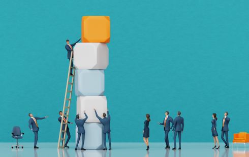 An image of miniature figures adding blocks to a stack and a ladder to show the idea of climbing the career ladder at work.