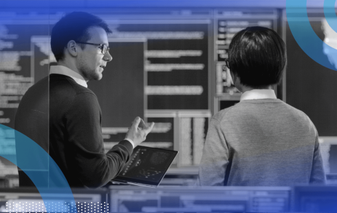 Two engineers talk with a tablet computer in front of servers