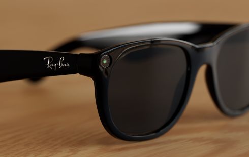 A pair of Meta Ray-Ban smart glasses rest on a wooden surface.