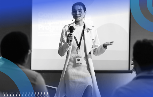 A woman in a business suit gives a presentation in front of a screen