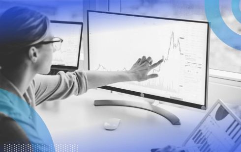 A financial analyst looks at dashboards on computer screens