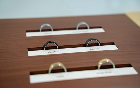 Three pairs of Oura Rings are lined up on a wood table.