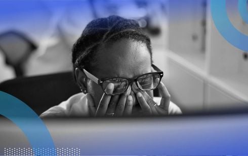 A developer rubs their eyes while looking at a computer screen