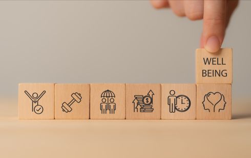 A photo of wooden blocks with physical, mental and emotional health icons to show the idea of employee wellbeing.