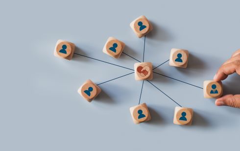 A photo of wooden blocks and a hand, with lines uniting the block to one with a handshake to show the idea of shared team culture. 