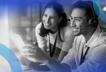 Two tech team members are smiling and looking at a computer screen.