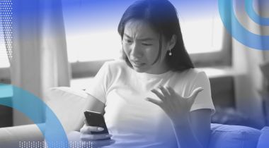 A woman looking angrily at a cell phone. Mercury in retrograde can spark communication snafus, so move carefully to avoid them.