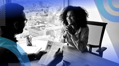A man interviewing a woman in an office high-rise.