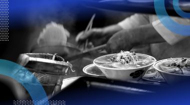 A pair of hands making ramen with two finished bowls of ramen next to him.