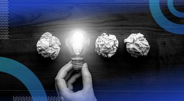 Three pieces of crumpled up paper and a hand holding a lit up lightbulb in a row.