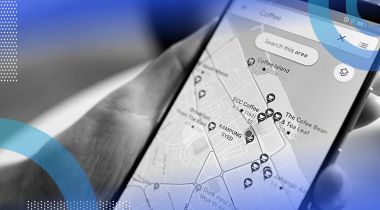 A hand holding a phone showing a Google Maps search for “coffee.”