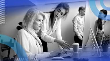 A younger woman criticizes an older woman who looks angry in front of a computer