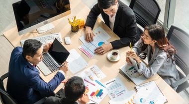 Office workers are pictured collaborating in a conference room.