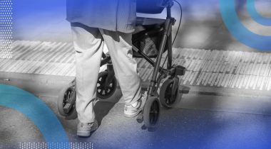 An elderly person using a walker with wheels on a cut curb.