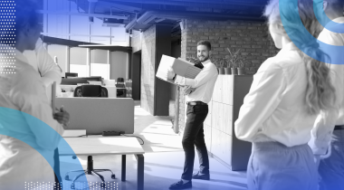 A person holding a box is saying goodbye to colleagues.