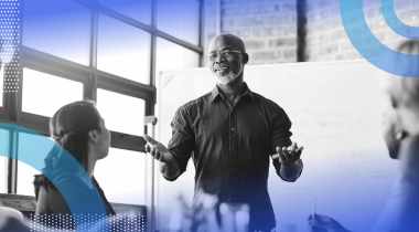 A businessman gives a pitch in front of a whiteboard