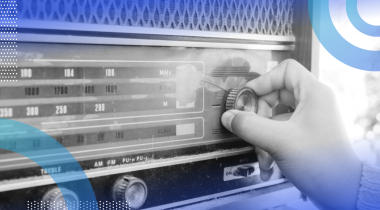 A close-up of a hand tuning an old-fashioned stereo.