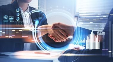 A photo of business people shaking hands over a hologram of financial bar charts and data security elements.