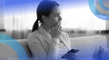 A woman holds a smartphone and looks worried