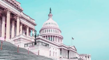 Front facade of Capitol building with light blue background.