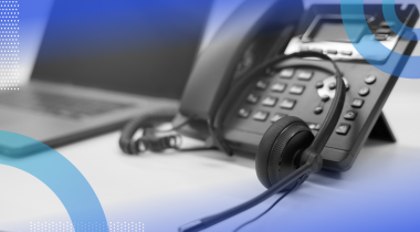 A business phone with a headset and a laptop