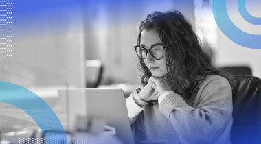 A young woman with glasses looks intently at a computer