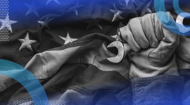 A gloved hand holds a wrench in front of an American flag