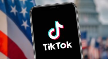 A smartphone with TikTok on it against the backdrop with the U.S. Capitol and American flags.