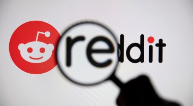 A magnifying glass zooms in on the Reddit logo.