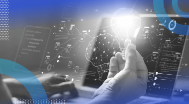 A user works at a laptop while holding a light bulb