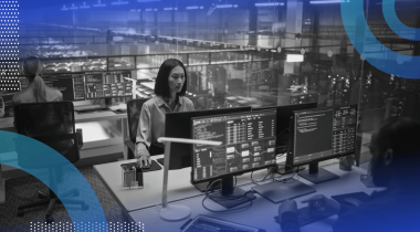 IT workers on terminals in an office with glass walls