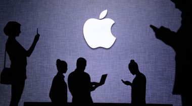 Silhouettes of people using technology in front of Apple logo