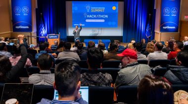 A group of Optimum employees in the audience of a hackathon.