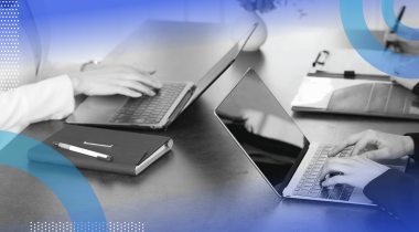 A closeup on developers working on laptops with a notebook on the table